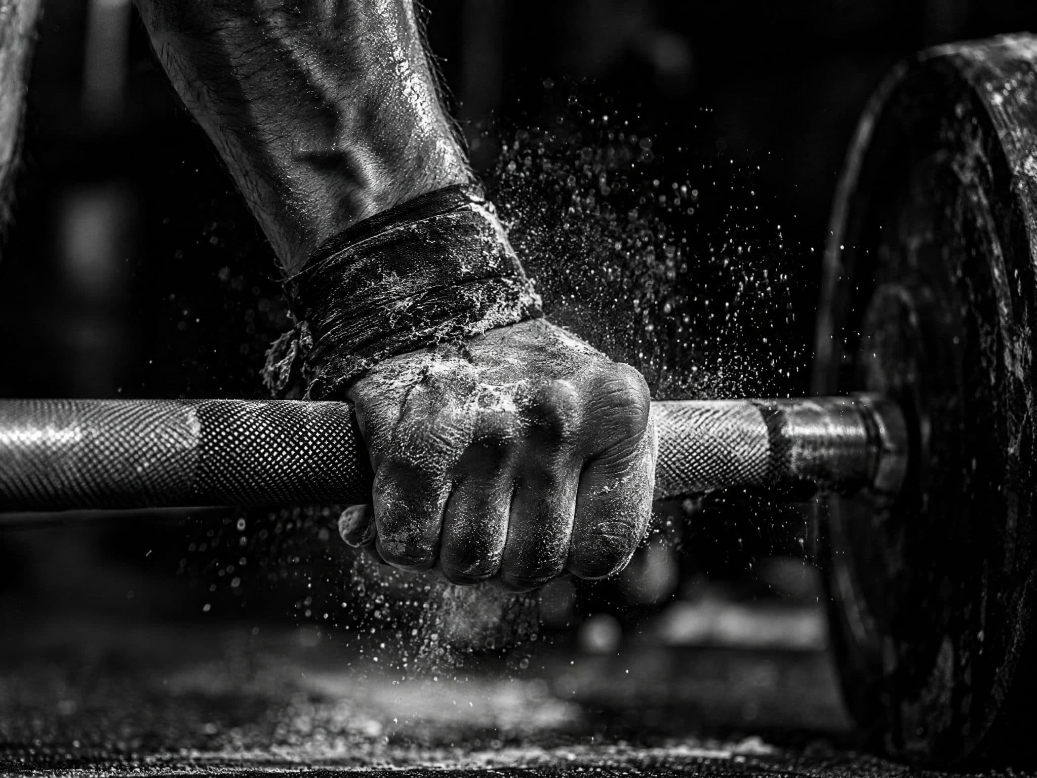 Chalked hand gripping a barbell