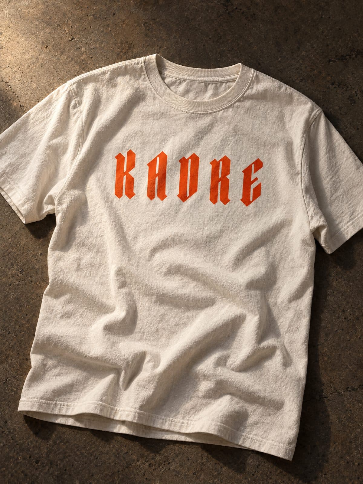 Off-white t-shirt with the KADRE wordmark in orange